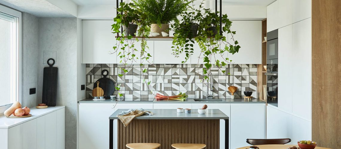 Stylish kitchen interior design with dining space. Workspace with kitchen accessories on the back ground. Creative walls with woode pannels. Minimalistic style an plant love concept.